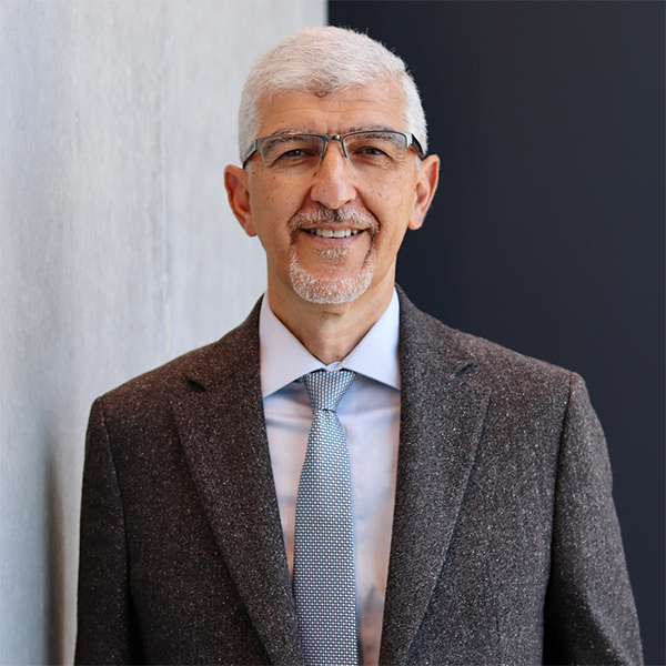 Portrait image, torso up, of a man with short white hair and glasses in a suit, Dr. Ashraf
